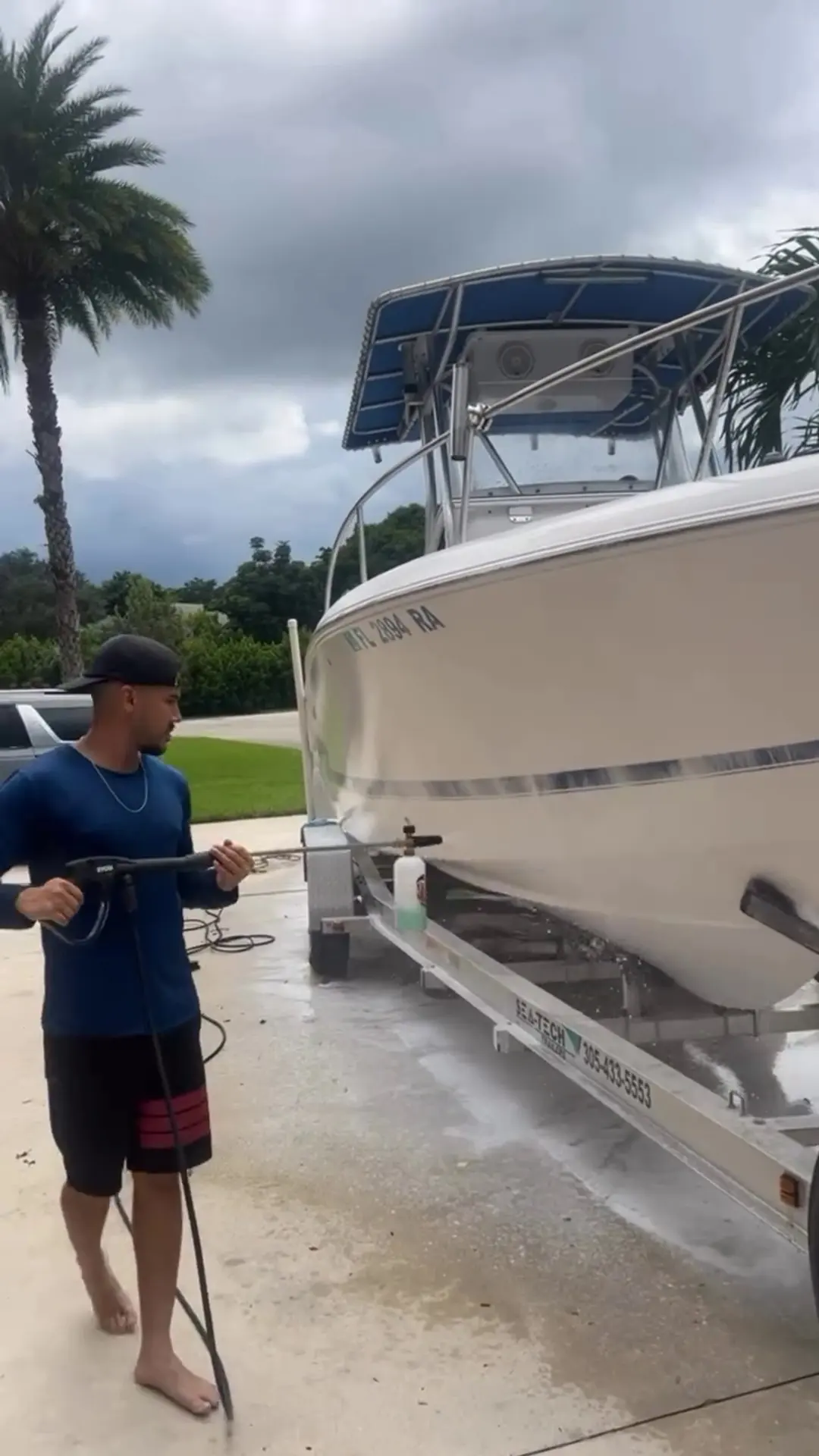 Detailer washing a center console boat on its trailer