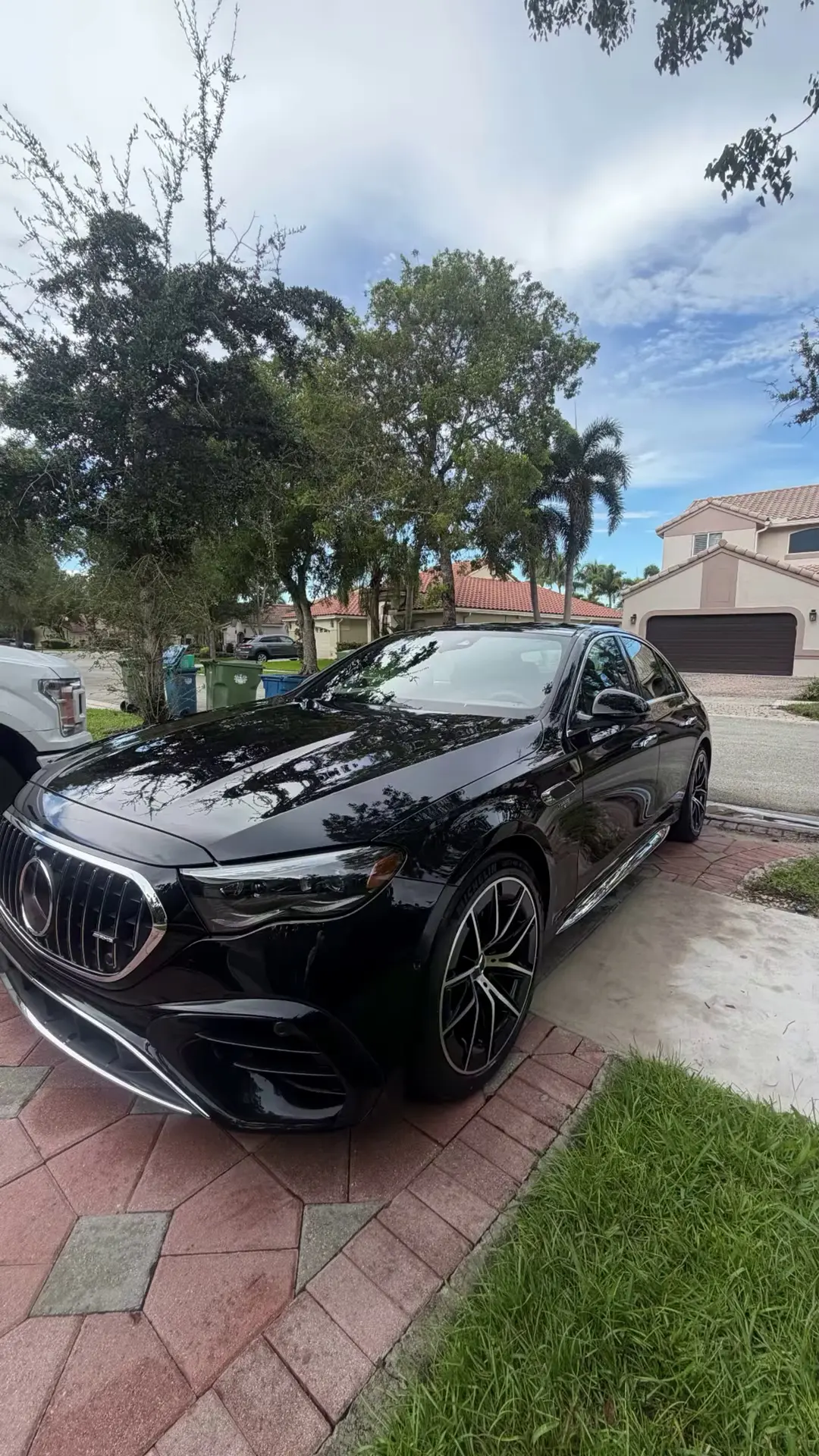 Black Mercedes-AMG sedan, freshly detailed, in a sunny driveway with palm trees