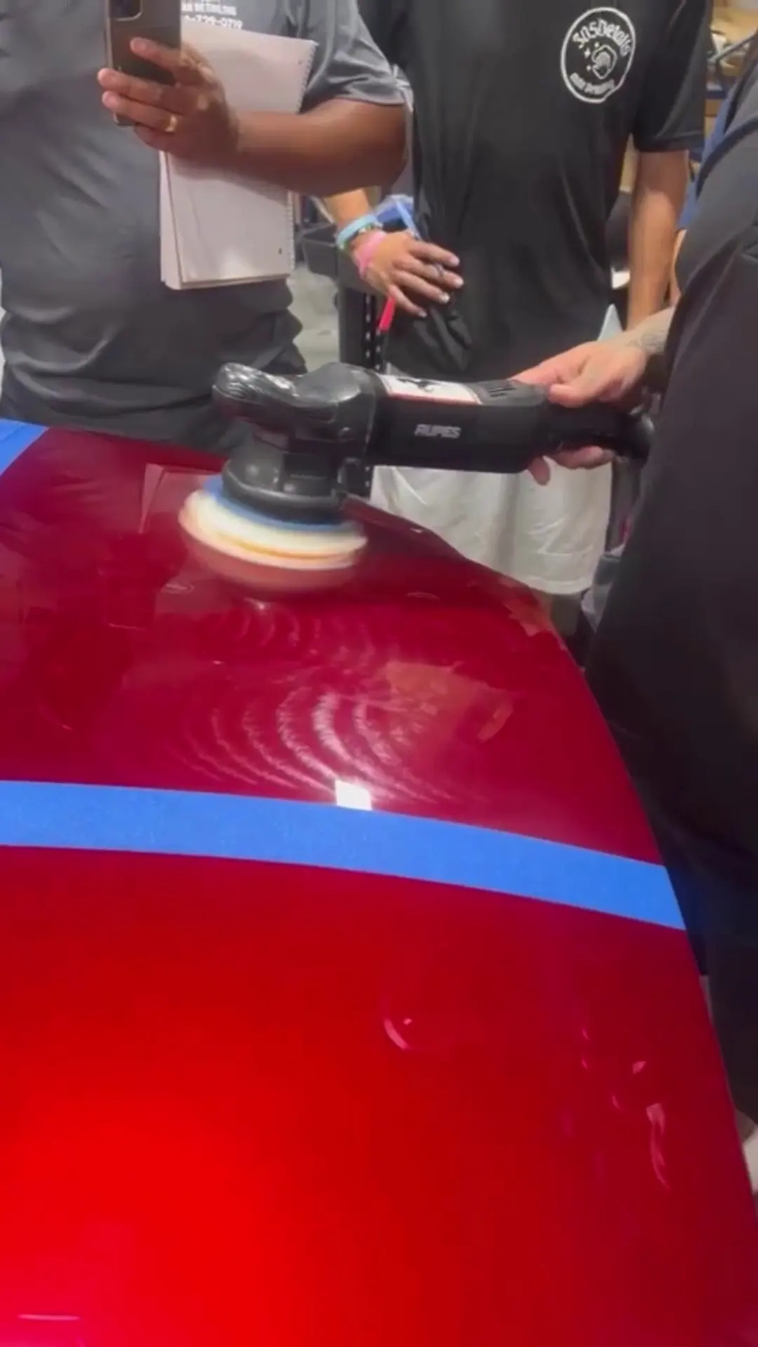Machine polishing a red panel during paint correction training