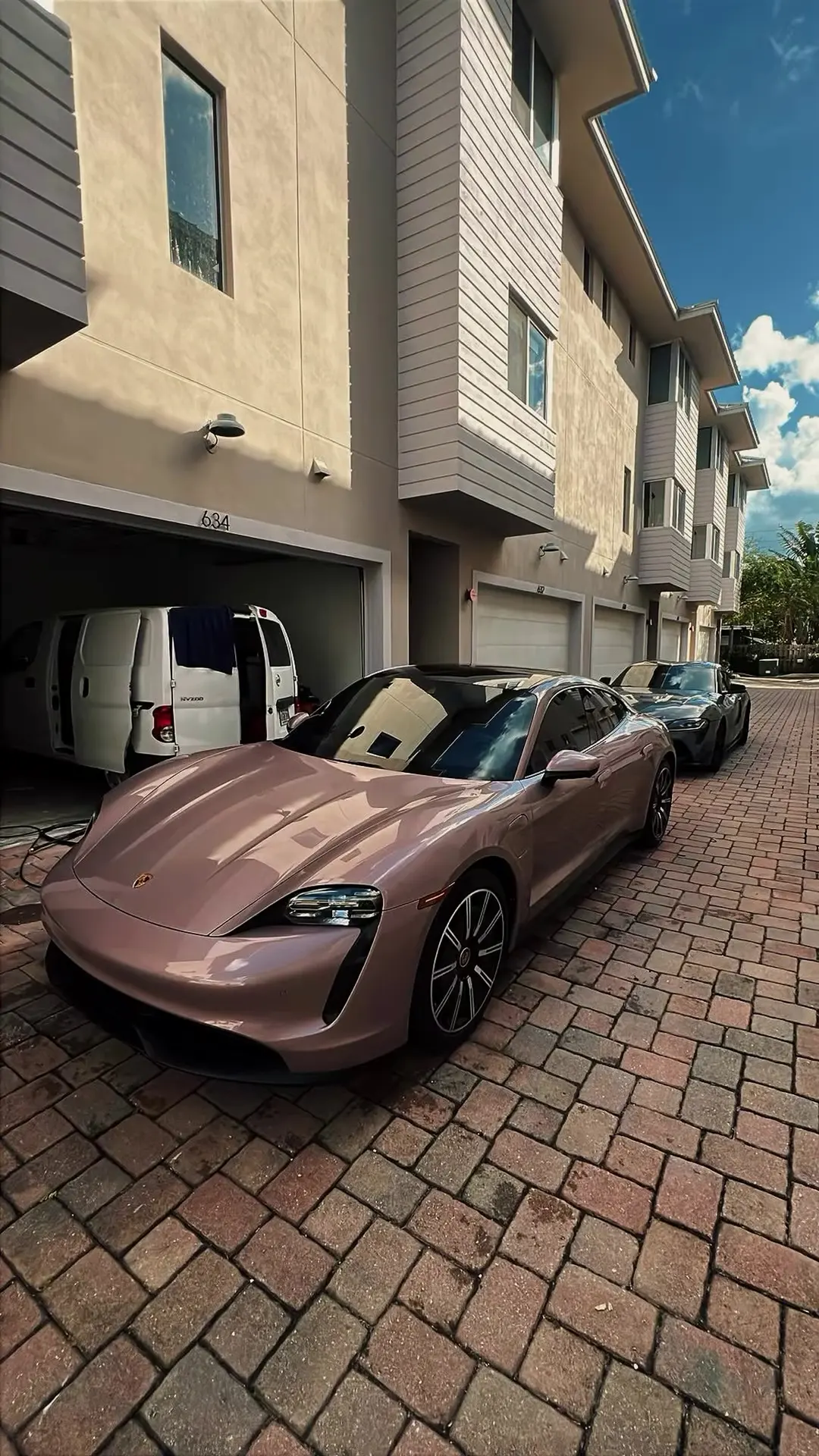 Rose gold Porsche Taycan after a detail, parked outside a townhouse