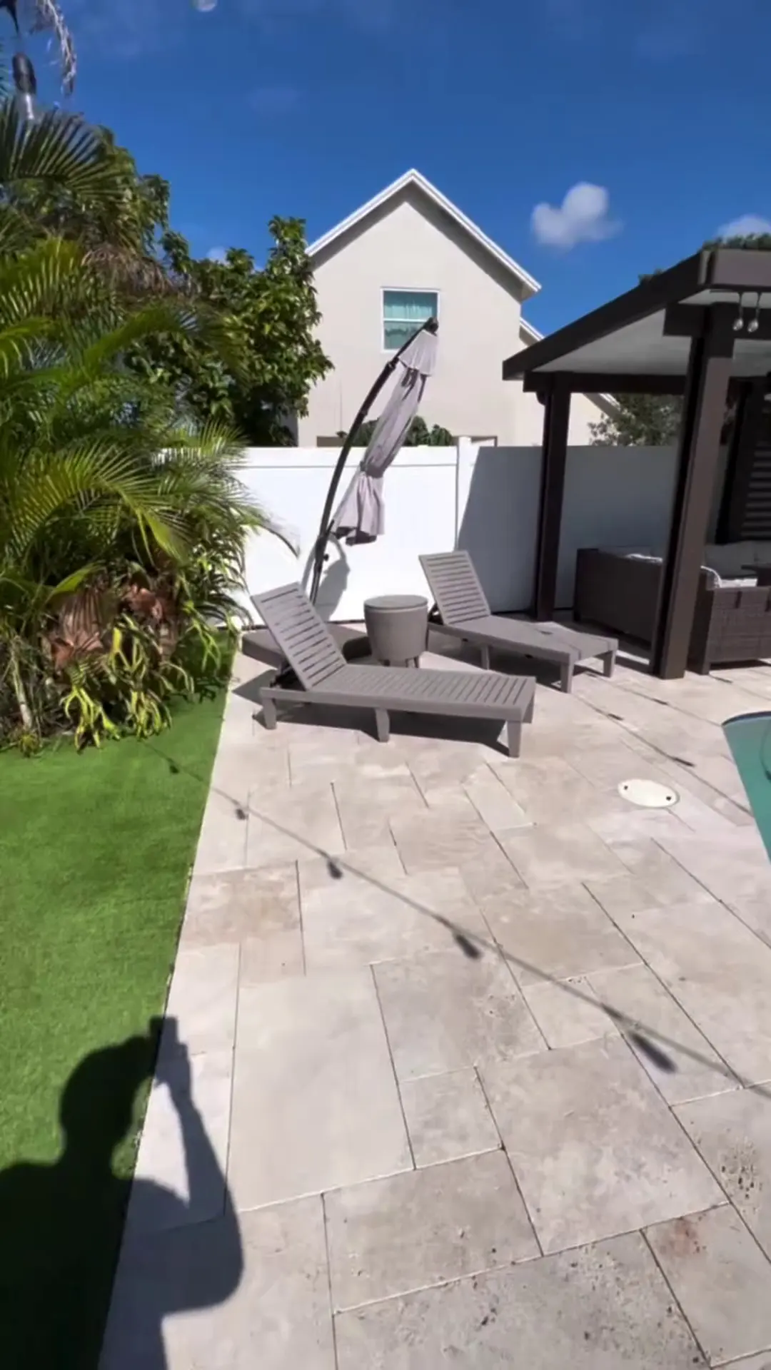 Clean travertine patio with loungers and a pergola after pressure washing