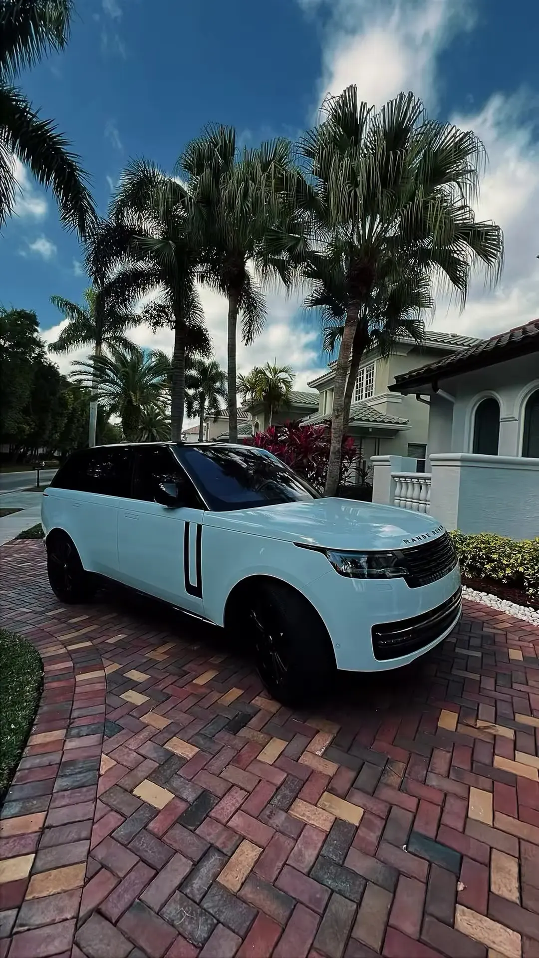 White Range Rover in a paver driveway lined with palm trees after a detail